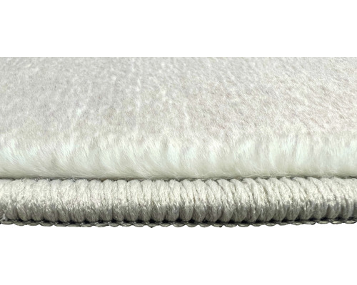 Detailopname van een wit vloerkleed met lange pool