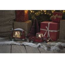 Decoratieve scène met een rode speelgoedtruck met aanhanger, kerstbomen en cadeaus
