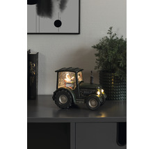 Decoratieve sneeuwbol tractor met kerstman op een kast