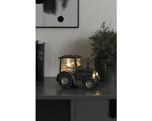 Decoratieve sneeuwbol tractor met kerstman op een kast