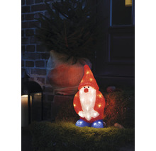 Decoratieve, verlichte kabouter staat voor een huis naast een kerstboom.