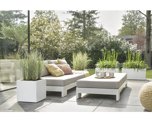 Buitenscène met bank, kussens, tafel, servies en planten in plantenbakken