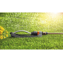 Tuinscene met gazonsproeier in gebruik