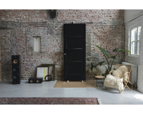 Kameroverzicht met zwarte deur, luidsprekers, fauteuil en decoratie voor een bakstenen muur