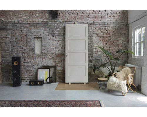 Loftruimte met bakstenen muur, deur, luidsprekers en fauteuil.