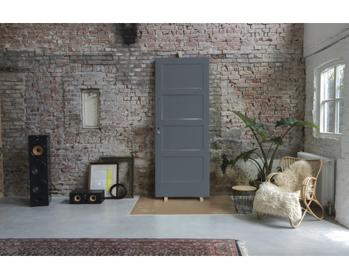 Interieur met grijze deur, luidsprekers, fauteuil en bakstenen muur