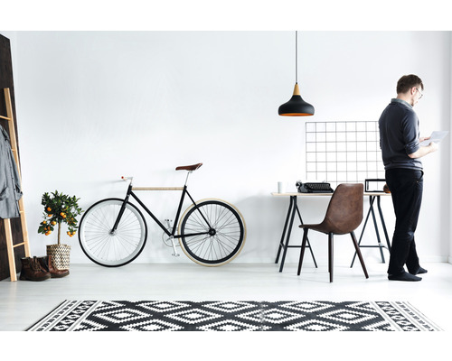 Lichte studeerkamer met bureau, stoel, fiets aan de muur en een persoon