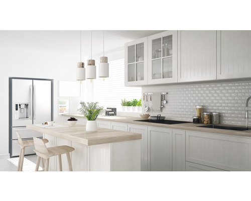 Lichte keuken met kookeiland, stoelen, koelkast en hanglampen.