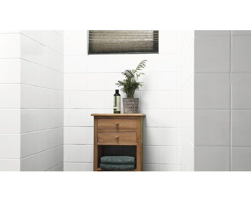 Badkamer met witte tegels, houten kast, plant en rolgordijn