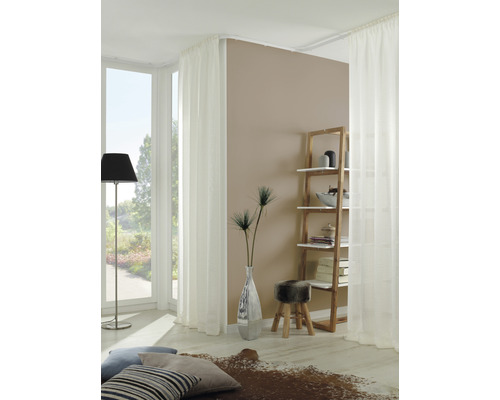 Lichte woonkamer met witte gordijnen, houten rek en decoratieve elementen.