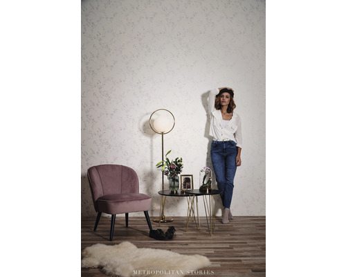 Woonkamer met fauteuil, bijzettafel en staande lamp voor een wand met motief