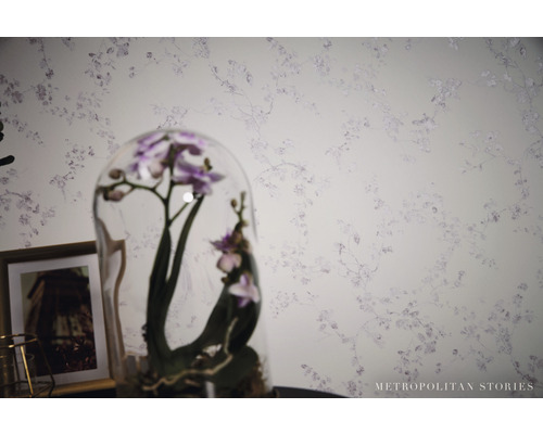 Close-up van een muur met bloemenbehang en een orchidee onder een glazen stolp.