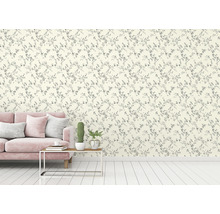 Een woonkamer met een bank en een muur met bloemenbehang