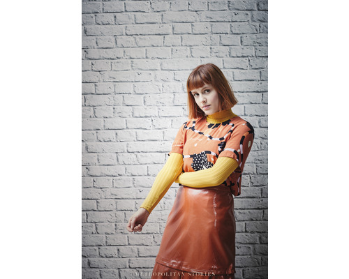 Vrouw met T-shirt met print en glanzende rok voor een bakstenen muur