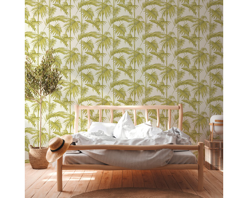 Een slaapkamer met een bed en behang met bladmotief.