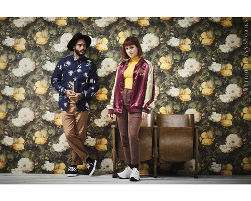 Twee mensen poseren voor een muur met bloemdecor