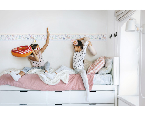 Kinderkamer met eenhoornrand en spelende kinderen op een bed met laden