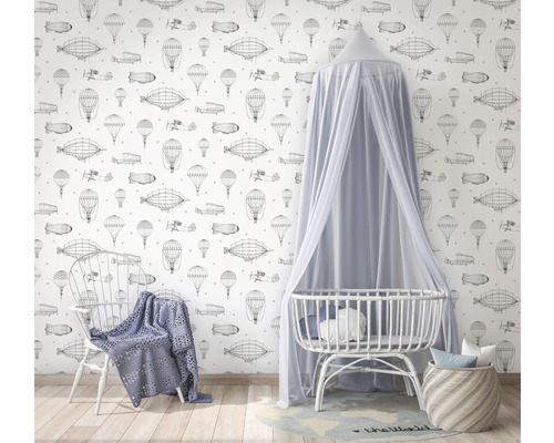 Kamer met behang met luchtvaartthema''s, babybedje met hemel en stoel met deken