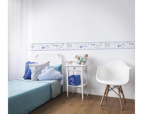 Kinderkamer met rand met ruimtemotieven, bed, nachtkastje en stoel.