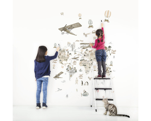 Twee kinderen beschilderen een wereldkaart muursticker met vliegtuig-, luchtballon- en diermotieven.