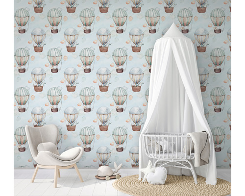 Kinderkamer met behang met heteluchtballonnen, fauteuil en wieg met baldakijn