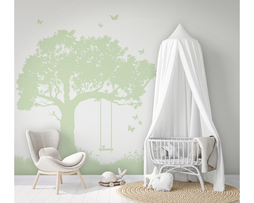 Kinderkamer met boom muursticker, stoel en wieg met baldakijn.