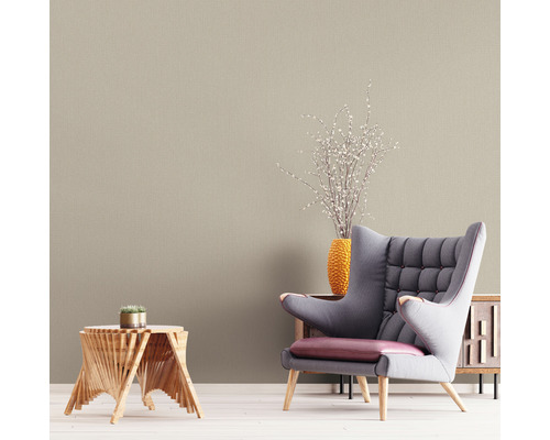 Woonkamer met beige behang, fauteuil en houten tafel