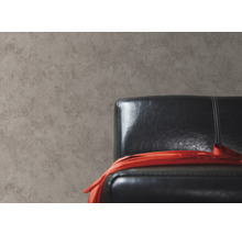 Close-up van een grijze muur met een zwarte lederen fauteuil en een rode doek