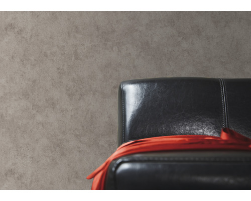 Close-up van een grijze muur met een zwarte lederen fauteuil en een rode doek