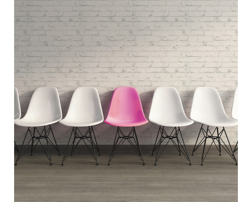 Rij stoelen met een enkele gekleurde stoel voor een muur