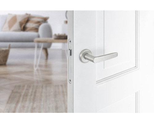 Geopende witte binnendeur met zilverkleurige deurklink in een woonkamer