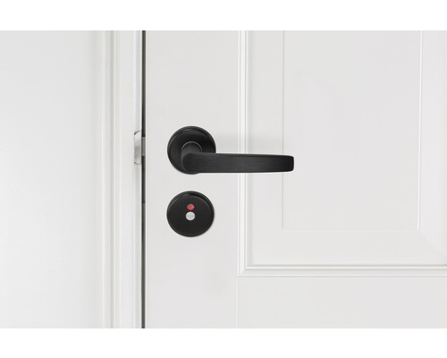 Zwarte deurklink met draaiknop op witte deur