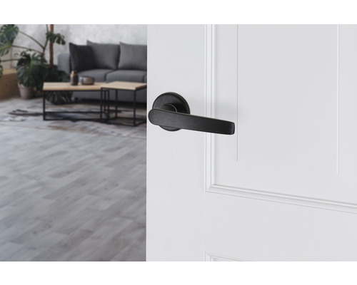 Zwarte deurklink op een witte deur in een lichte woonkamer