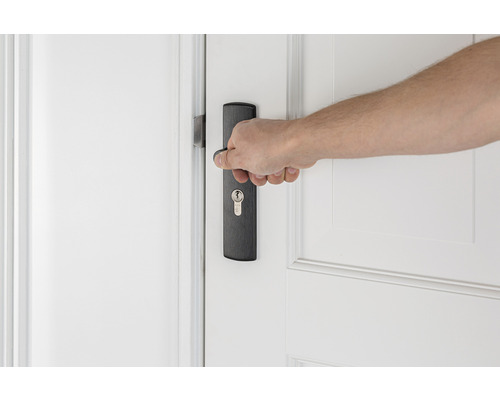 Hand bedient deurklink op een binnendeur