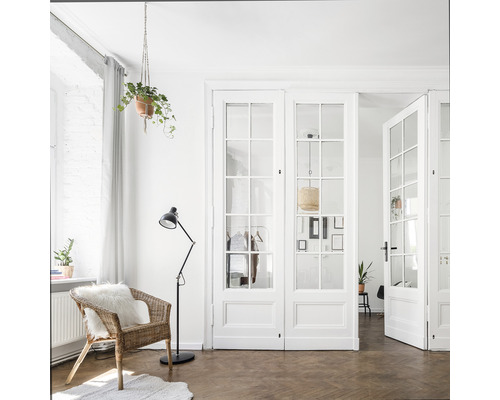 Lichte woonkamer met rieten stoel, vloerlamp en dubbele glazen deur