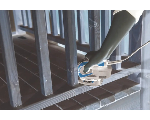 Een persoon gebruikt een WORX-multischuurmachine om een houten leuning te schuren.