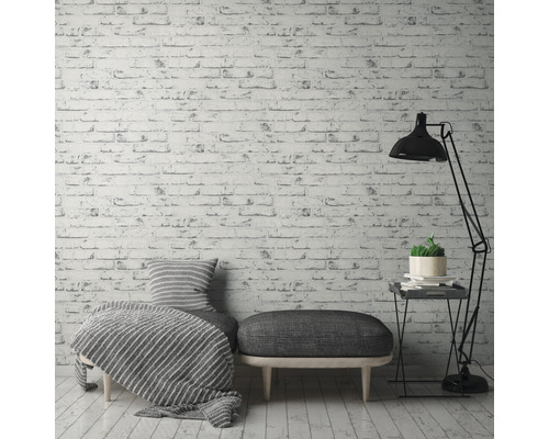 Decoratieve woonkamer met baksteenmotiefbehang, zitmogelijkheid, staande lamp en bijzettafel.