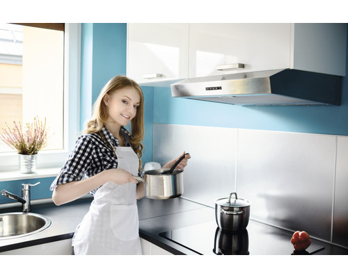 Lichte keuken met vrouw die kookt, kookpannen en afzuigkap.