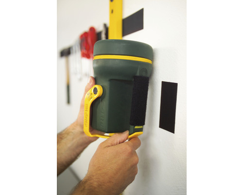 Groen multifunctioneel gereedschap met klittenbandsluiting wordt aan een muur bevestigd