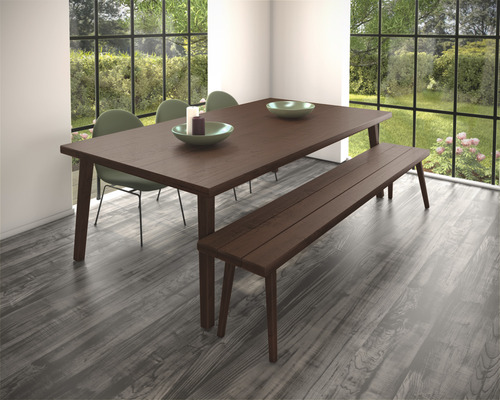 Eetkamer met houten tafel, bank en stoelen voor een raam met uitzicht op de tuin