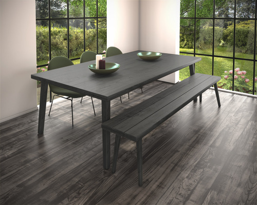 Eetkamer met houten tafel, bank en stoelen voor een raam met uitzicht op de tuin