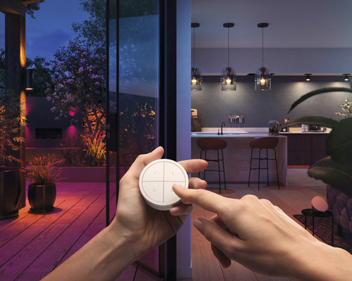 Scène met een persoon die een lichtschakelaar bedient voor een verlicht terras en een binnenkeuken