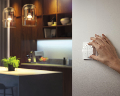 Een hand bedient een lichtschakelaar in een modern ontworpen ruimte.