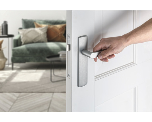 Een hand opent een witte binnendeur met een zilverkleurige deurklink.