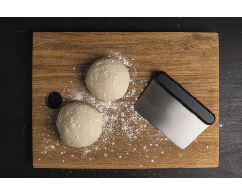 Houten plank met porties deeg, deegschraper en bloem