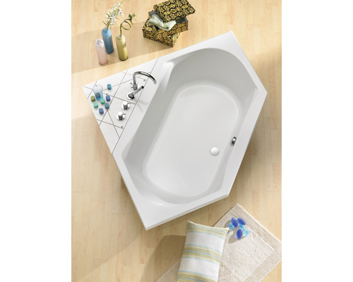 Hoekbad in de badkamer met kraan en decoratieve artikelen op de badrand.