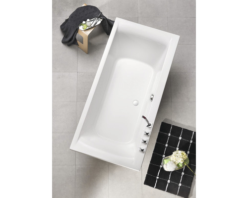 Rechthoekig bad in badkamer met armaturen en decoratie