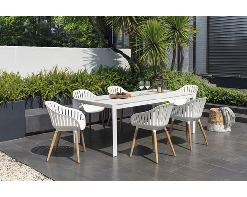 Tuinscene met een witte eettafel en zes stoelen buitenshuis