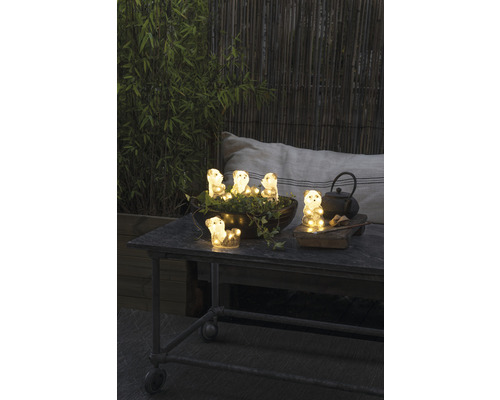 Decoratieve verlichtingsfiguren in de vorm van beren op een tuintafel met theeaccessoires