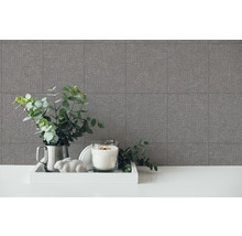 Decoratieve opstelling met behang met patroon, kaars en groene planten op een tafel